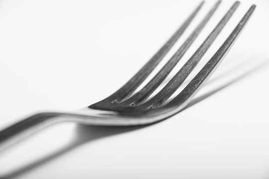 A single silver fork on a white background showing regular wear and tear