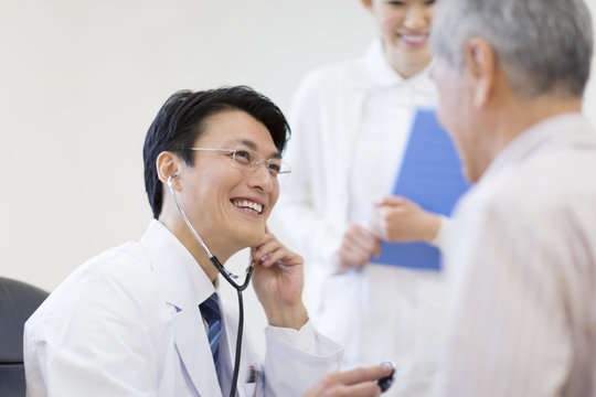 Male doctor examining patient with stethoscope