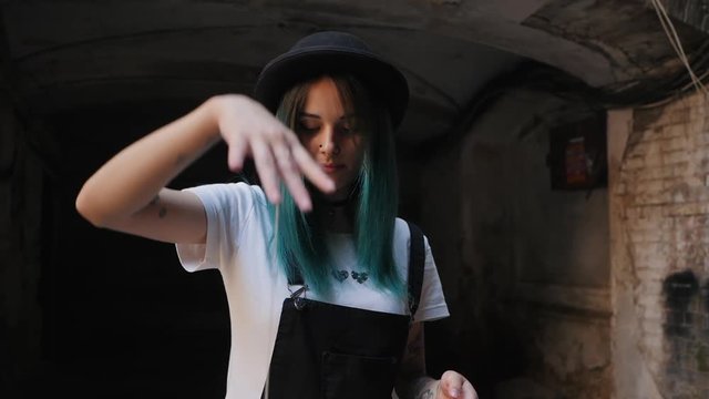 SLOW MOTION: emo girl playing with old school toy yo yo. Street punk or hipster with blue dyed hair,piercing,lenses,tattooed,ears tunnels and unusual hairstyle stands in backyard.