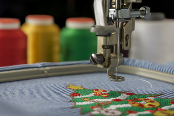 Macro picture of embroidery machine finish work christmas tree design on fabric stripes white and...