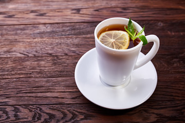 Green tea with lemon and mint on wooden table background