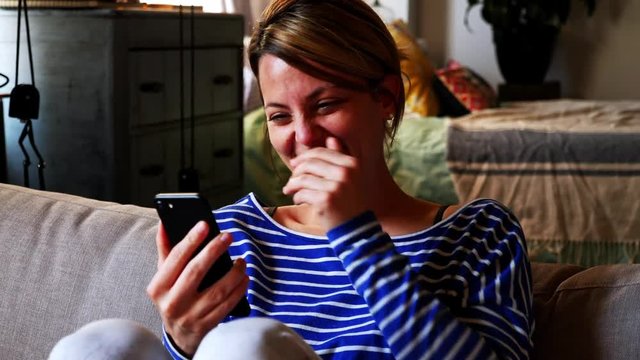 People relations. Two girls are speaking and using cellphone on sofa