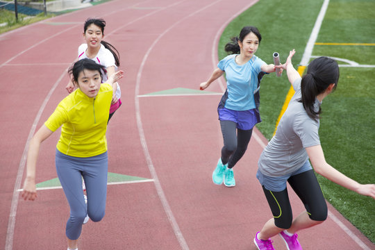 Female students in an athletic fieldpassing batons