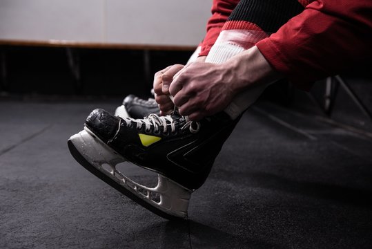 Low section of hockey player tying ice skate