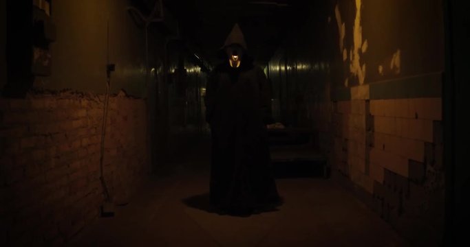A frightening man in a mask in a long hallway