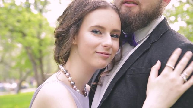in love a beautiful couple, a girl in a lilac dress and a man with a beard in a jacket walking in the park