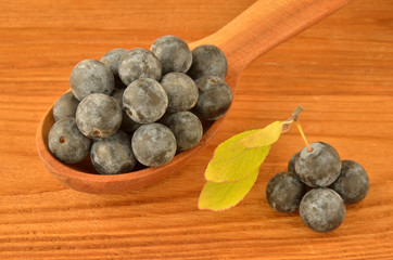 Spoon with blackthorn on a wooden board. Close-up