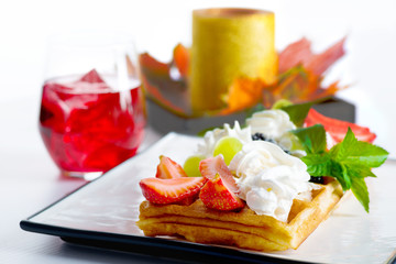 wafers with berries and cream on a plate and autumn maple leaves
