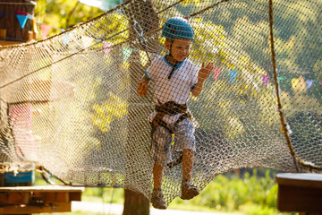 Fototapeta na wymiar The boy climbs a rope park