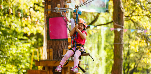 happy little girl in a rope park on the wood background