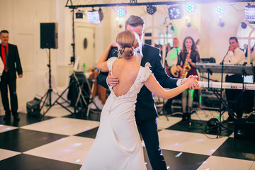 gorgeous stylish happy bride and groom performing their emotional first dance, wedding in a restaurant