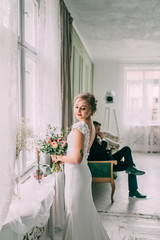 cute wedding couple in the interior of a classic studio decorated. they kiss and hug each other. Newkyweds looking. Bride and groom photoshoot