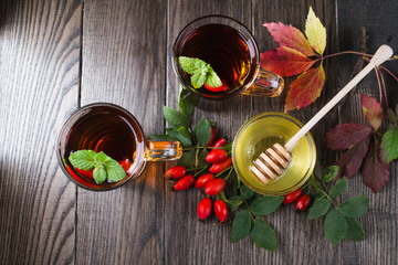 Healthy autumn drink with hip roses ,branch with berries on dark  background. Top view