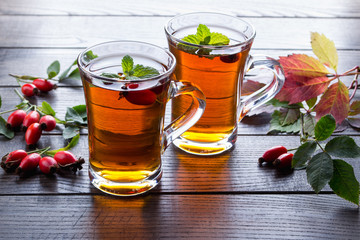 Healthy autumn drink with hip roses ,branch with berries on dark  background. 