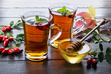 Rose hip tea in transparent cup with honey and fresh berries. Vitamin C drink on dark  background.