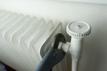 Central heating, white radiator with hand tool repairing