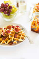 Healthy breakfast: Belgian waffles with figs, grapes and caramel on white table cloth. Selective focus