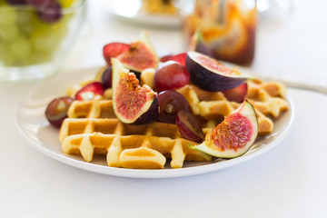 Healthy breakfast: Belgian waffles with figs, grapes and caramel on white table cloth. Selective focus