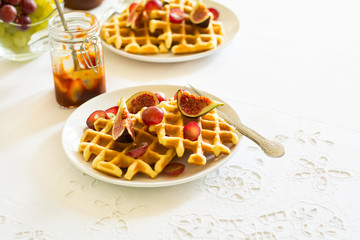 Healthy breakfast: Belgian waffles with figs, grapes and caramel on white table cloth. Selective focus