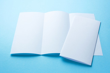 Leaflet blank tri-fold white paper brochure mockup on blue background