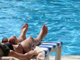 Slim girl sunbaths on a lounger near the pool