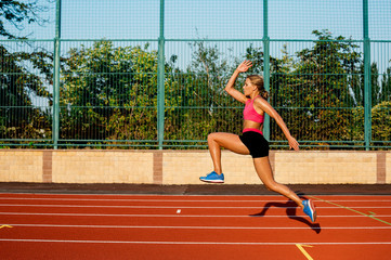 Obraz premium Side view beautiful young woman exercise jogging and running on athletic track on stadium