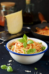 Pasta with tomato and basil in bowl on the background of ingredients
