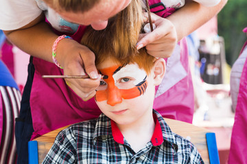 Child boy face painting, making tiger eyes process