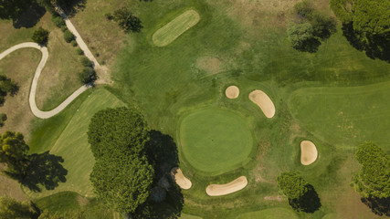 Vista aerea di un campo da golf con ostacoli di sabbia, enormi prati e albero che rendono più difficile il gioco.Il sole splende ed è una giornata ideale per fare sport e stare alla aria aperta.