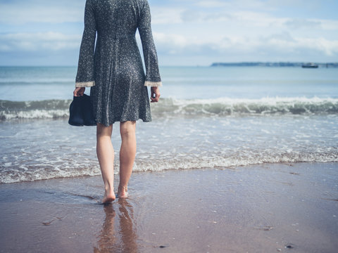 Woman on beach with shoes in her hand