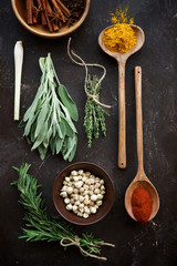 Variety of spices in bowls and spoons,bunches of fresh herbs.  Top view