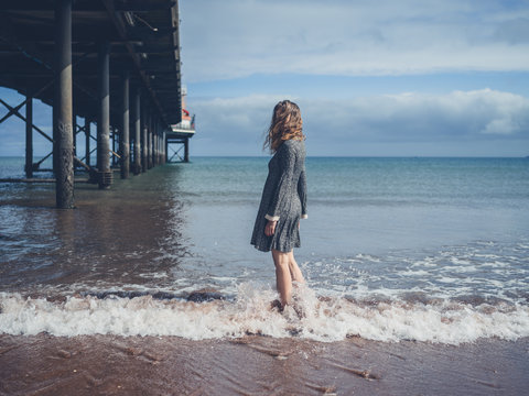 Young woman standing by a pier on the beach