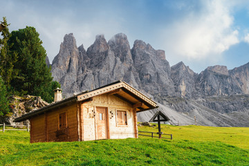 Fototapeta na wymiar Wooden cottage overlooking the impressive Dolomites rock formation in northern Italy
