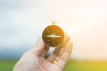 Hand with compass at green natural background.Compass on hand with blurred background.selective...