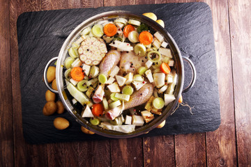 Bone broth made from chicken with carrots, onions various fresh vegetables in a pot - colorful fresh clear spring soup. Rural kitchen scenery bouillon or stock