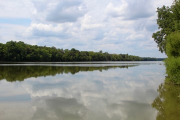 The reflecting clouds on the river water on a sunny day.