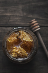 Jar of healthy real honey with honeycomb inside