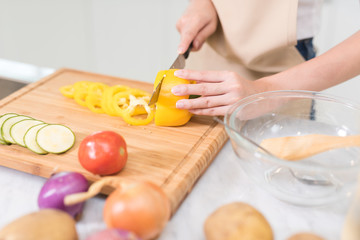 Female hand slicing paprika on cutting board at the kitchen, prepare the ingredient for cooking salad for her family