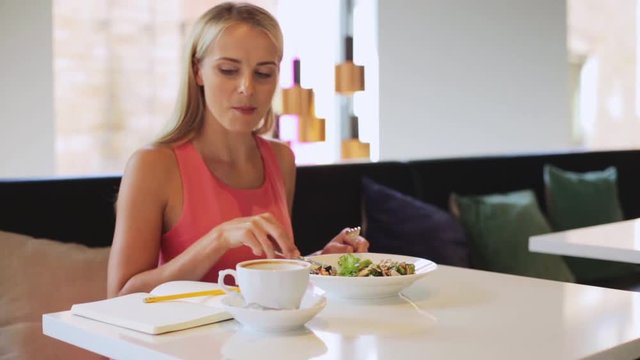 woman or reviewer eating lunch at restaurant