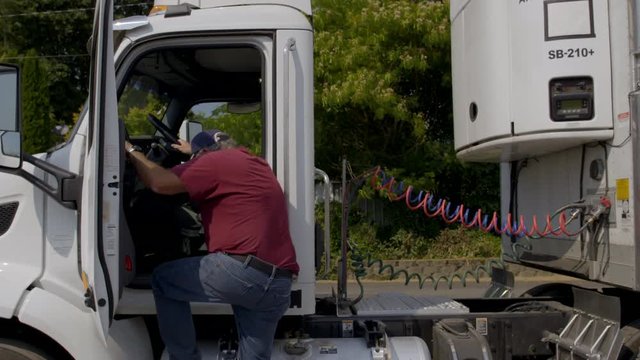 Driver opens door and climbs down from truck cab in daylight exterior, summer day. Side view, real-time 4K.