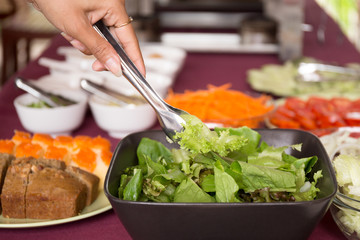 Selected focus woman taking fresh vegetable salad from salad bowl