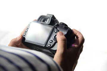 Woman photographer holding a digital camera reviewing the work. White background and empty copy space.