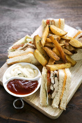classic club sandwich with fries on wooden board