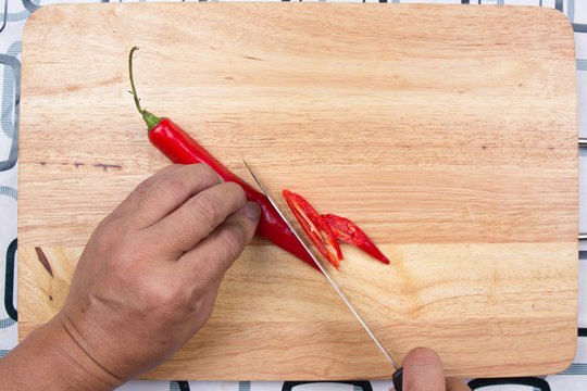 Hand cutting Hot Chili Peppers on wooden broad