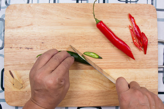 Hand cutting Hot Chili Peppers on wooden broad