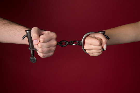 male and female hands are handcuffed.