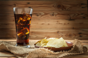 Potato chips with cola on a wooden background