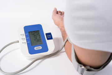 Digital Blood Pressure Monitor with the arm of a man on white background