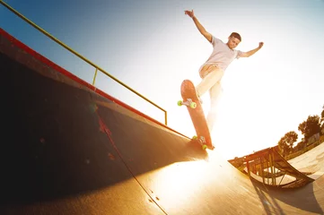Afwasbaar fotobehang Teen skater hang up over a ramp on a skateboard in a skate park © yanik88
