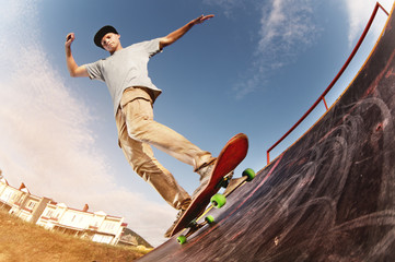 Teen skater hang up over a ramp on a skateboard in a skate park - obrazy, fototapety, plakaty